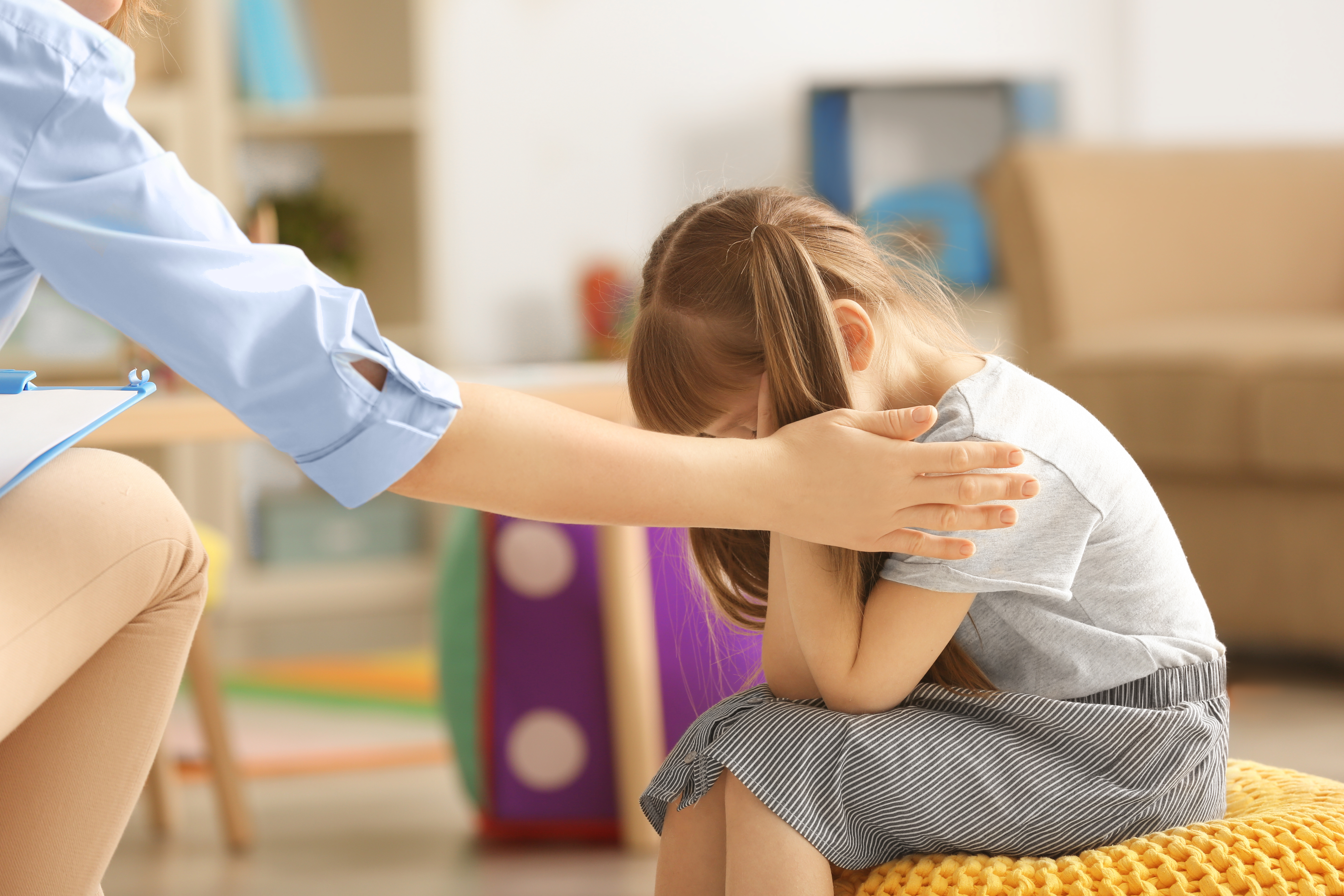 A therapist soothes a young girl who is exhibiting a problem behavior